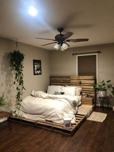 a bedroom with a bed made out of wooden pallets and plants on the wall