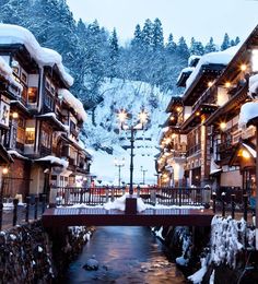 a river running through a snow covered town next to tall buildings with lights on them