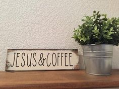 a potted plant sitting on top of a wooden table next to a sign that says jesus and coffee