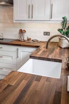 a kitchen with white cabinets and wooden counter tops, including a sink in the center