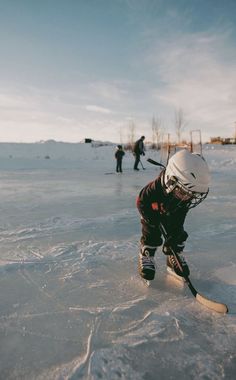 a young boy is skating on an ice rink with his helmet and hockey stick in hand