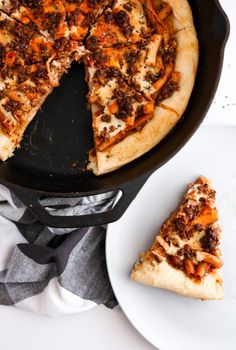 a pizza sitting on top of a pan next to a slice of pizza