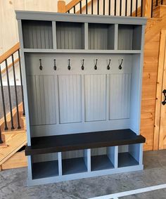 an entryway with two benches and several coat hooks on the wall, next to stairs