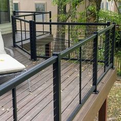 a deck that has some chairs on it and is next to a house with trees in the background