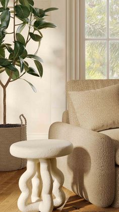 a living room with a couch, chair and potted plant on the floor in front of a window