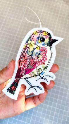 a hand holding an ornament with a bird painted on it's side