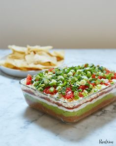 an appetizer dish on a marble table with chips and salsa in the background