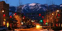 a city street at night with christmas lights and mountains in the background