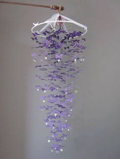 a wind chime with purple butterflies hanging from it's side and a white cloth draped over it