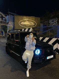 a man sitting on the hood of a black car in front of a building at night