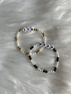 two bracelets with the word sun and moon written in white beads on a fur surface