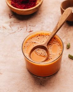 a wooden spoon sitting in a glass cup filled with liquid and some other items around it