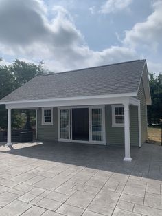 a small gray house with white trim on the roof