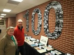 two people standing in front of a table with pictures on it and the words 100 are displayed behind them