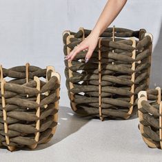 two baskets made out of sticks and wood are being held by a woman's hand