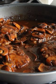 mushrooms are being cooked in a skillet on the stove with brown gravy