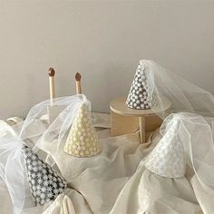 three small hats sitting on top of a white cloth covered tablecloth next to two wooden pegs