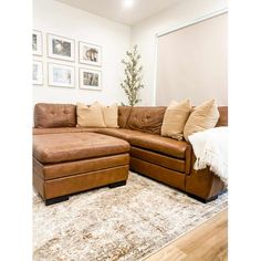 a living room with a large sectional couch and pillows on the rug in front of it