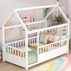 a child's bed with a white wooden frame and pink, yellow, green, orange and blue pillows