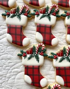 decorated cookies are arranged in the shape of christmas stockings and stocking decorations on a white tablecloth