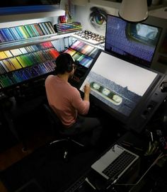 a man sitting at a desk in front of two monitors