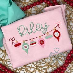 a personalized christmas ornament on a pink towel with red berries around it