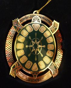 a gold and green turtle pendant on a black background