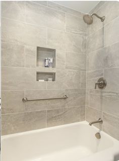 a white bath tub sitting inside of a bathroom next to a shower head and hand rail