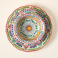 three colorful plates with designs on them sitting on a white surface, one has an orange center and the other is green