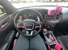 the interior of a car with pink trims and steering wheel, dash stickers