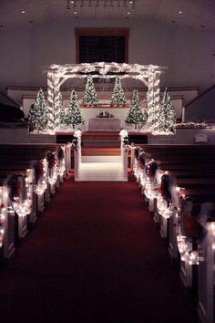 a church decorated for christmas with lights and trees on the alter, surrounded by candles