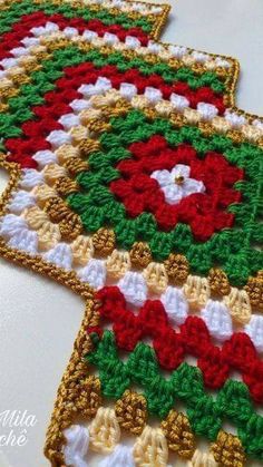 two crocheted rugs with red, white and green designs on them sitting on a table