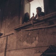 two people sitting on a ledge looking out the window