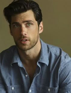 a man in a blue shirt looking at the camera with an intense look on his face