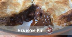 a close up of a pie in a pan on top of a wooden table with the words venison pie over it