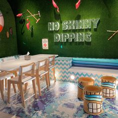 the interior of a restaurant with green walls and blue tile flooring, wooden chairs and tables