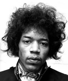 a black and white photo of a man with curly hair wearing a vest, bow tie and jacket