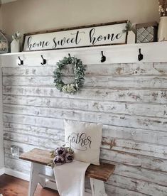 a wooden bench sitting in front of a white wall with two signs on it and a wreath