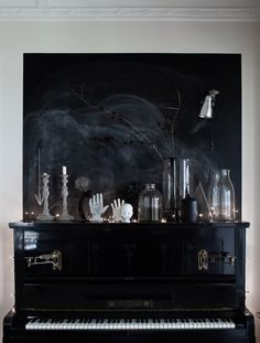 a black piano in front of a chalkboard with candles and vases on it