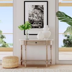 a white table with a potted plant next to it in front of two large windows