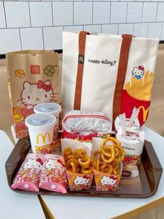 a tray filled with snacks and drinks on top of a table next to a hello kitty bag