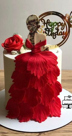 a woman in a red dress is sitting on top of a white cake with flowers