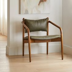 a chair sitting in front of a painting on the wall next to a wooden floor