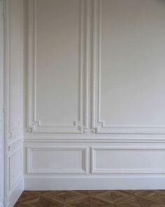 an empty room with white walls and wood floors