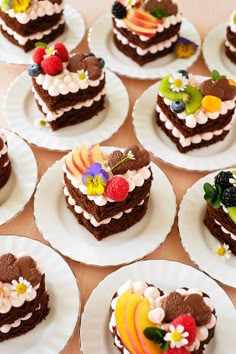 there are many heart shaped cakes on the plates with flowers and fruit toppings in them