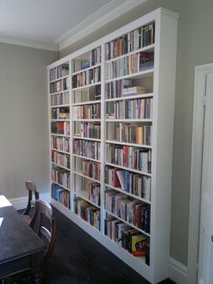 a large book shelf filled with lots of books on top of a hard wood floor