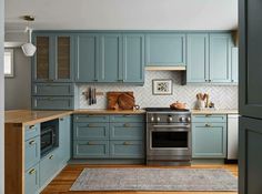 a kitchen with blue cabinets and wood flooring, including an oven in the center