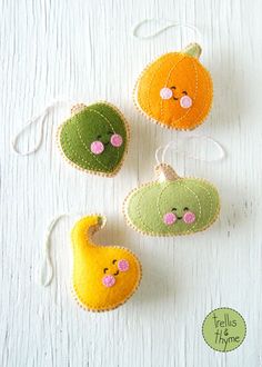 three felt pumpkins hanging from strings on a white surface