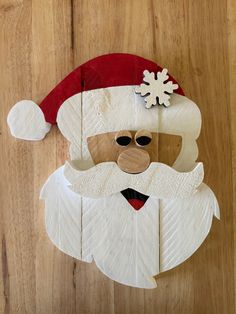 a paper mache of santa claus on a wooden surface with snowflakes hanging from his hat