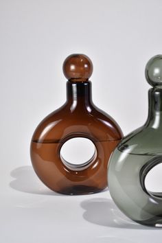 two vases sitting next to each other on a white surface with no one around them